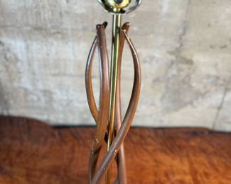 This lot features a mid-century modern sculptural table lamp, made of walnut and brass. Minor wear throughout as shown in photos and light turns on periodically (will need to some servicing or love). This lamp measures, 38” H x 7” W x 7” D.