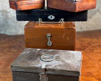 This lot features a collection of boxes from the 19th and 20th century. The two smaller ones up top are crafted from leather, the two below from wood, and the one in front is metal.