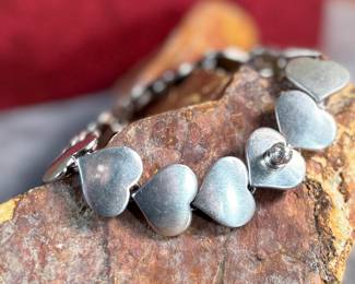 This lot features an iconic sterling silver hearts bracelet, a delightful classic design by Danish modernist Karl-Gustav Hansen for Hans Hansen, made in Denmark circa 1950s. Karl Gustav Hansen was the son Hans Hansen and later merged with the Georg Jensen company. This bracelet has the Hans Hansen designed screw-down clasp lock, measures 7” with a total approx. weight of 28.80 grams. Maker mark present as shown in photos.
