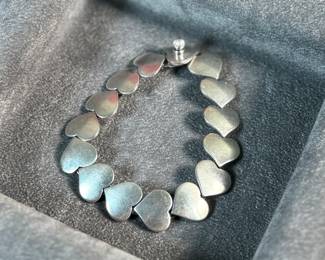 This lot features an iconic sterling silver hearts bracelet, a delightful classic design by Danish modernist Karl-Gustav Hansen for Hans Hansen, made in Denmark circa 1950s. Karl Gustav Hansen was the son Hans Hansen and later merged with the Georg Jensen company. This bracelet has the Hans Hansen designed screw-down clasp lock, measures 7” with a total approx. weight of 28.80 grams. Maker mark present as shown in photos.