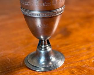 This lot features a 1873 birth commemorative sterling silver footed cup retailed by Ohio jeweler & silversmith, William Wilson McGrew (1833-1893). This silver cup was made to commemorate the birth of Nathaniel Foster Wilshire, son of George Wilshire who was a railroad and business tycoon. This cup measures, 5.25” H x 2.75” W x 4” D with a total approx. weight of 176.61 grams. Maker marks present underneath as shown in photos.