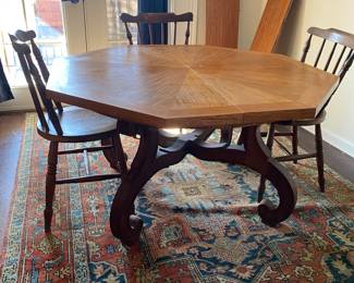 Octagonal Table with ornate legs. 4 primitive wooden dining chairs.