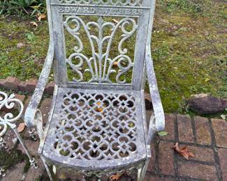 The image shows an antique cast iron cemetery chair, also referred to as a garden or patio chair. These chairs are a type of Victorian-style cast iron furniture popular in the late 19th and early 20th centuries. The name "EDWARD WITHERS" is visible on the back of the chair.