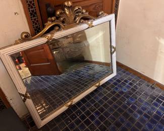 Statement white-and-gold wall mirror with ornate crest.