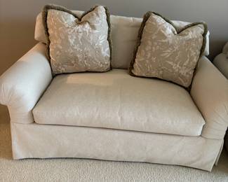Matching loveseat in ivory upholstery with matching decorative pillows