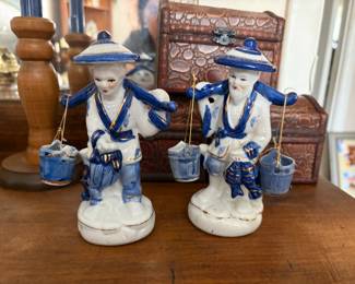 The image is of a vintage Chinese blue and white porcelain figurine, often described as a fisherman or a water carrier. 
