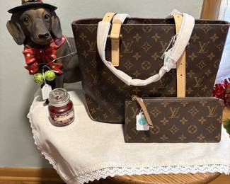 This happy pup is celebrating the holidays by displaying several of the high end purses and related items we have for purchase.