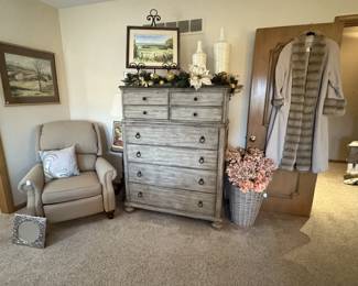 In the corner is a clean ivory recliner.  The chest is one of several matching pieces in the master bedroom.  Several pieces of original art.