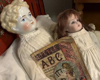 The china head doll is getting ready for night in her bed with original paint.  The ABC linen book might help her sleep, but it is awfully cute. Her bed mate is another German bisque doll.