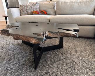 $750      "Live Edge Coffee Table
Room: Living Room
Solid teak root wood painted black with a sturdy black steel
frame.
*Item will vary in shape/size due to natural wood edging.
46""W x 37""D x 15.5""H"		