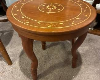 Round wood side table featuring inlaid floral motif. 