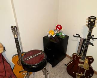 Lots of musical and sound equipment- guitars, stool, speakers, sound boards.

