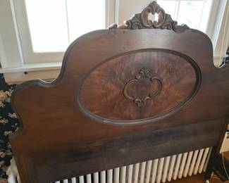 Antique full-size bed with ornate headboard.