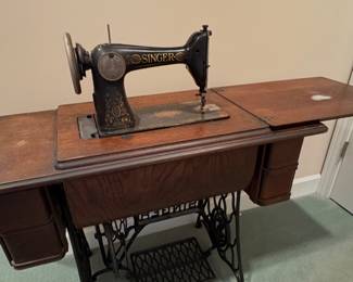 vintage Singer treadle sewing machine in a wooden cabinet.