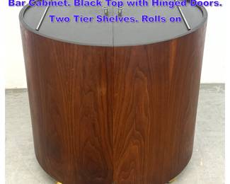 Lot 943 Mid Century Modern Walnut Round Bar Cabinet. Black Top with Hinged Doors. Two Tier Shelves. Rolls on