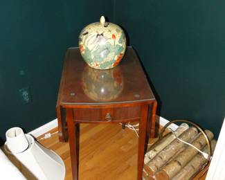 Antique drop-leafed table with glass protection, and apple shaped Asian inspired vase, along with birch logs is brass birch log holder