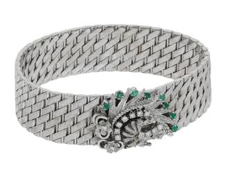 "This stunning vintage bracelet is crafted from luxurious 18k white gold and features a captivating design adorned with sparkling diamonds and vibrant emeralds. Measuring 19 cm in length and 1.7 cm in width, this exquisite piece weighs 71.1 grams and boasts a diamond weight of 0.3 ct. The intricate woven pattern and peacock-inspired design make it a standout accessory for any occasion, embodying elegance and sophistication. This bracelet is not just a piece of jewelry; it's a statement piece that showcases both artistry and opulence.

Victorins Auctions will coordinate all domestic and international shipping. Please allow approximately 10–15 business days for processing. Certain items may require additional handling time depending on their location, origin, or special packaging requirements. By registering for or placing a bid in a Victorins auction, you confirm that you have reviewed, understood, and agreed to our Shipping, Payment, and Auction Policies."
