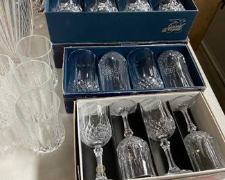 Crystal stemware along with a table full of glass trays, bowls, and serving pieces