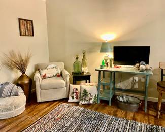 Neutral color side chair and neutral tweed ottoman, great small desk, flat screen TV, decorative pillows and numerous home decor items,