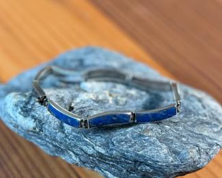 This lot features a vintage silver lapis modernist set including a hinged bib necklace, a bracelet, and earrings. Marked .970 silver with a total approx. weight of 51.89 grams. The necklace measures 16”, bracelet 8”, and earrings 1.5” H.
