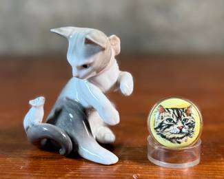 This lot features a porcelain figurine titled, "Cat and Mouse", manufactured by Lladro (model number 5236) & a cat themed trinket box manufactured by Bilston and Battersea. Bilston and Battersea enamels are fine English enamelware, originally produced in the 18th century and revived in the 20th century, known for decorative items like trinket boxes, pillboxes, and other luxury goods
