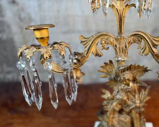 This lot features an antique, mid-19th century Victorian brass triple-light girandole candelabra with crystal prisms and a white marble base. This candelabra measures, 18” H x 15” W x 4” D. 
