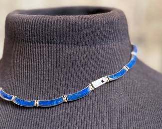 This lot features a vintage silver lapis modernist set including a hinged bib necklace, a bracelet, and earrings. Marked .970 silver with a total approx. weight of 51.89 grams. The necklace measures 16”, bracelet 8”, and earrings 1.5” H.
