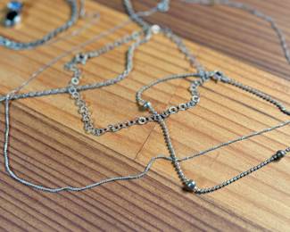 This lot features a collection of sterling silver jewelry including bracelets, chains, and a pendant with a total approx. weight of 23.84 grams.
