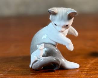 This lot features a porcelain figurine titled, "Cat and Mouse", manufactured by Lladro (model number 5236) & a cat themed trinket box manufactured by Bilston and Battersea. Bilston and Battersea enamels are fine English enamelware, originally produced in the 18th century and revived in the 20th century, known for decorative items like trinket boxes, pillboxes, and other luxury goods
