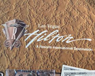 The Las Vegas lot! This lot features two coins featuring .999 fine silver, a bag of proof nickels, a new sealed card set, three (3) silver certificates, and a Baccarat table cover from The Hilton in Las Vegas.
