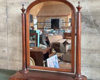 This lot features an antique American Empire gentleman’s shaving mirror with a tilt-top frame, fluted upright supports, and a shaped base with bun feet. This mirror measures, 33” H x 30” W x 12” D.
