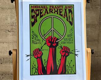 This lot features a concert poster for Michael Franti & Spearhead, designed and signed by artist, Justin Hampton. Limited edition, numbered 94/150 and measures, 25.5” H x 17.5” W. The concert was presented by the House of Blues and took place at the Paramount Theatre in Seattle. 
