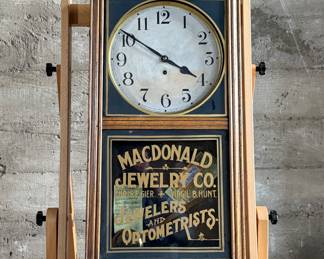 This lot features an antique clock made by the Waterbury Clock Company, with an advertising glass panel for Macdonald Jewelry Company. Appears complete with key, pendulum, instructions, and service records. This clock measures, 35” H x 16” W x 5” D. The Waterbury Clock Company factory is a historic complex of factory buildings in Waterbury, Connecticut. Development began in 1873, with the extensive plant serving as the company’s main manufacturing facility and headquarters until 1944.
