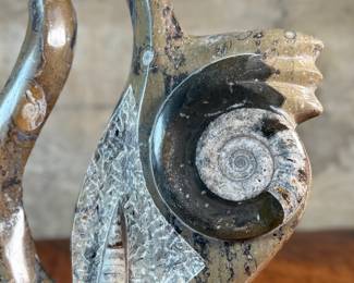 This lot features a stunning polished fossil sculpture featuring embedded ammonite and orthoceras fossils. This sculpture measures, 17.5” H x 12” W x 4” D.
