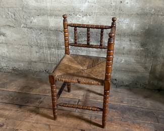 This lot features a Dutch bobbin corner chair with a rush seat, likely from the 1920s that measures, 29” H x 16” W x 16” D.
