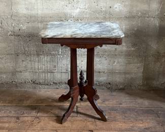 This lot features an antique Eastlake Victorian carved walnut parlor table with a marble top that measures, 28.5” H x 24” W x 16” D.
