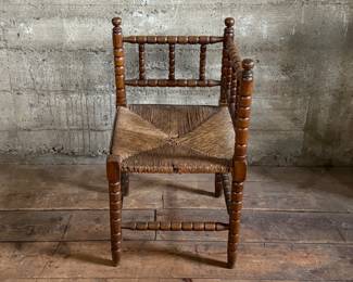 This lot features a Dutch bobbin corner chair with a rush seat, likely from the 1920s that measures, 29” H x 16” W x 16” D.
