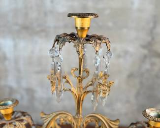 This lot features an antique, mid-19th century Victorian brass triple-light girandole candelabra with crystal prisms and a white marble base. This candelabra measures, 18” H x 15” W x 4” D. 
