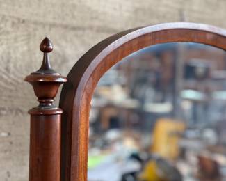 This lot features an antique American Empire gentleman’s shaving mirror with a tilt-top frame, fluted upright supports, and a shaped base with bun feet. This mirror measures, 33” H x 30” W x 12” D.
