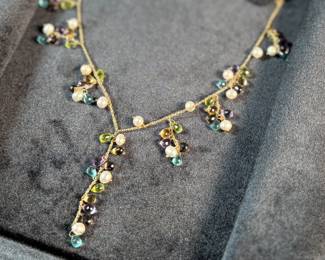 This lot features a stunning vintage 10k gold necklace with various stones including Amethyst, Peridot, Pearl, Blue Topaz, & Citrine, measuring 18” with a total approx. weight of 11.26 grams. Comes in a fancy presentation case and marked 10k as shown in photos.
