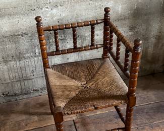This lot features a Dutch bobbin corner chair with a rush seat, likely from the 1920s that measures, 29” H x 16” W x 16” D.
