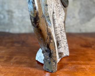 This lot features a stunning polished fossil sculpture featuring embedded ammonite and orthoceras fossils. This sculpture measures, 17.5” H x 12” W x 4” D.
