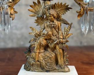 This lot features an antique, mid-19th century Victorian brass triple-light girandole candelabra with crystal prisms and a white marble base. This candelabra measures, 18” H x 15” W x 4” D. 
