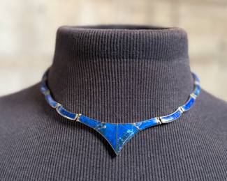 This lot features a vintage silver lapis modernist set including a hinged bib necklace, a bracelet, and earrings. Marked .970 silver with a total approx. weight of 51.89 grams. The necklace measures 16”, bracelet 8”, and earrings 1.5” H.
