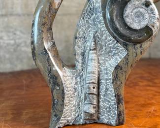 This lot features a stunning polished fossil sculpture featuring embedded ammonite and orthoceras fossils. This sculpture measures, 17.5” H x 12” W x 4” D.
