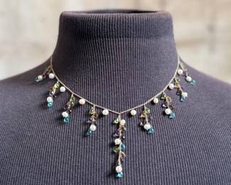 This lot features a stunning vintage 10k gold necklace with various stones including Amethyst, Peridot, Pearl, Blue Topaz, & Citrine, measuring 18” with a total approx. weight of 11.26 grams. Comes in a fancy presentation case and marked 10k as shown in photos.
