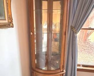 Oak corner curio cabinet with mirrored back and light. One of two available in this auction