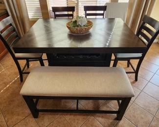 Bar height nearly new dining set. Set includes bench and four matching chairs. Table had storage underneath as well!