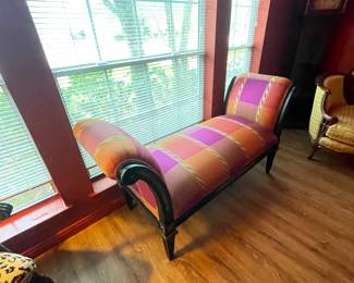 Chaise lounge with a vibrant, multi-colored plaid or checkered upholstery and a dark wood frame