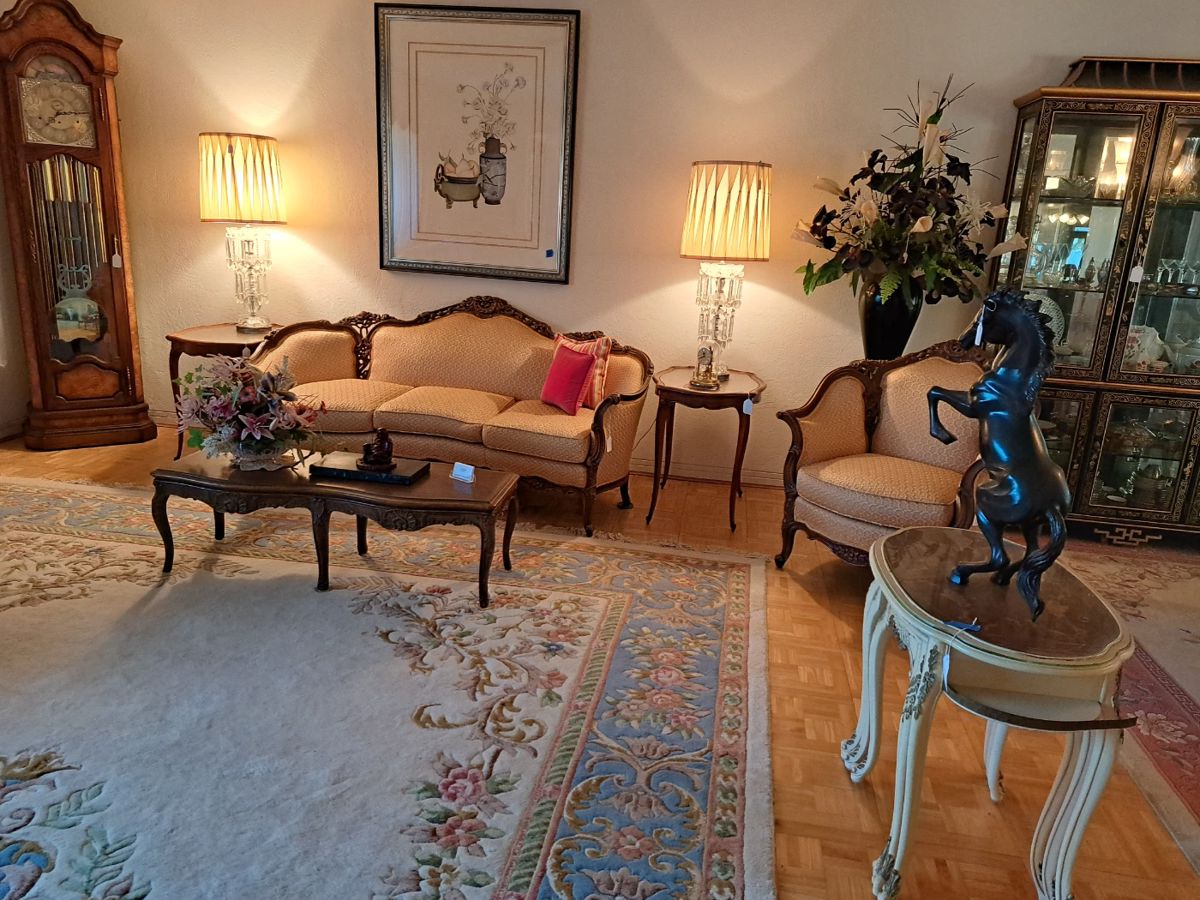 Part of living room with French inspired sofa and chair, large grandfather clock, side tables and crystal lamps